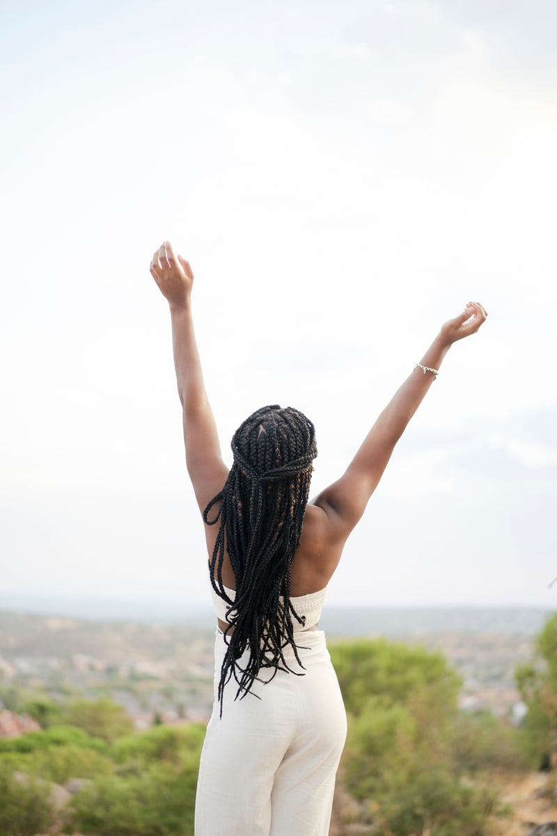 Black Woman with Braids Looking Away Raising Arms Standing in Mo